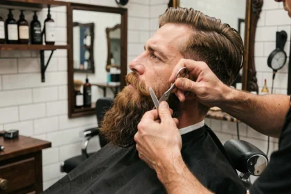 Barbier taillant et sculptant une longue barbe brune dans un salon de coiffure moderne